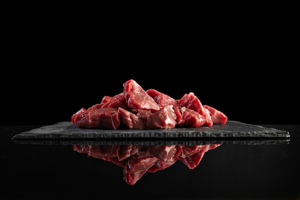 pieces-raw-fresh-meat-isolated-black-stone-board-mirrored-side-view_346278-817